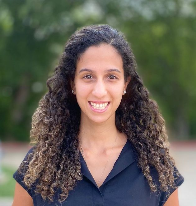 A woman with curly hair is smiling and wearing a black shirt.