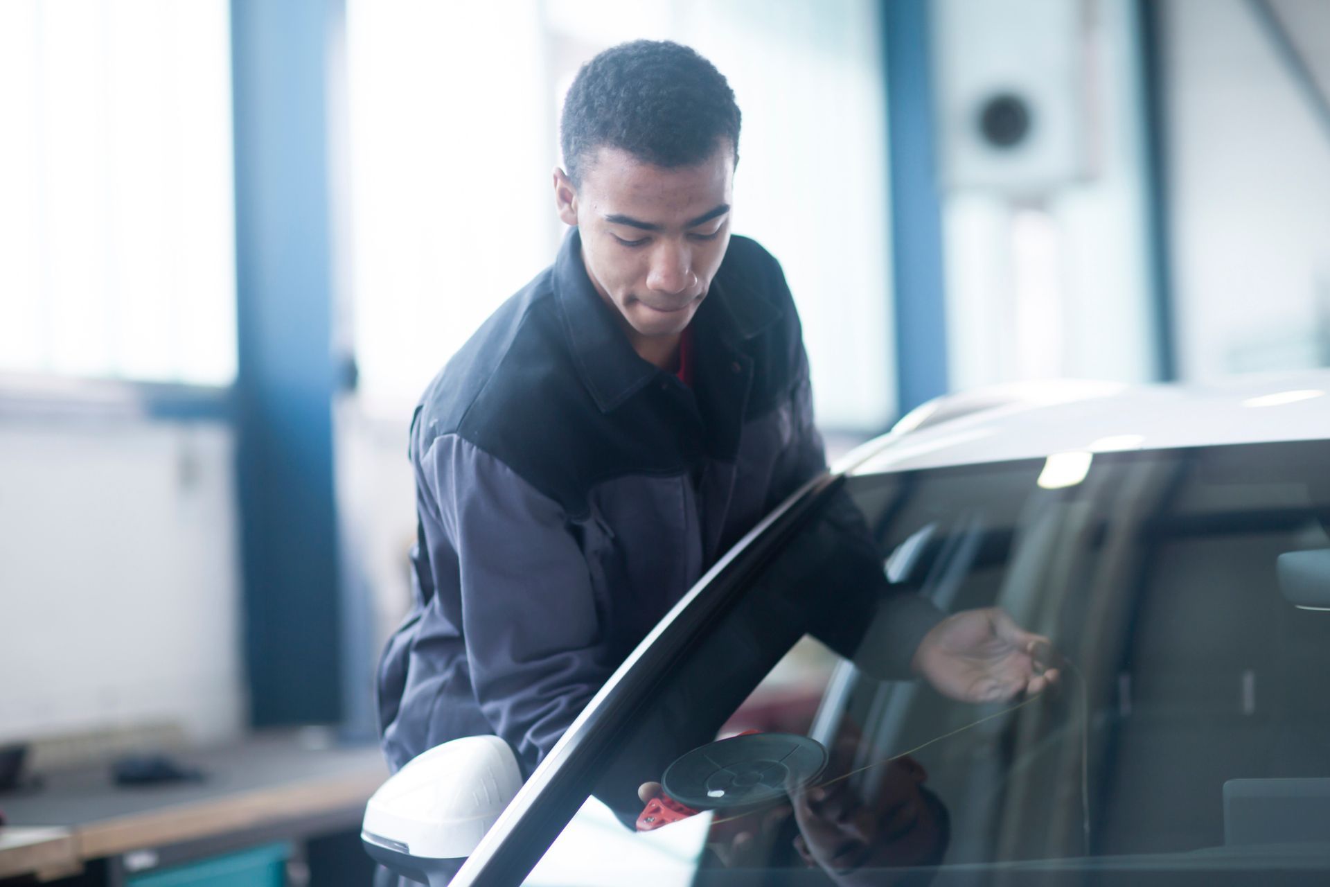 Workman fixing car windscreen in a workshop.