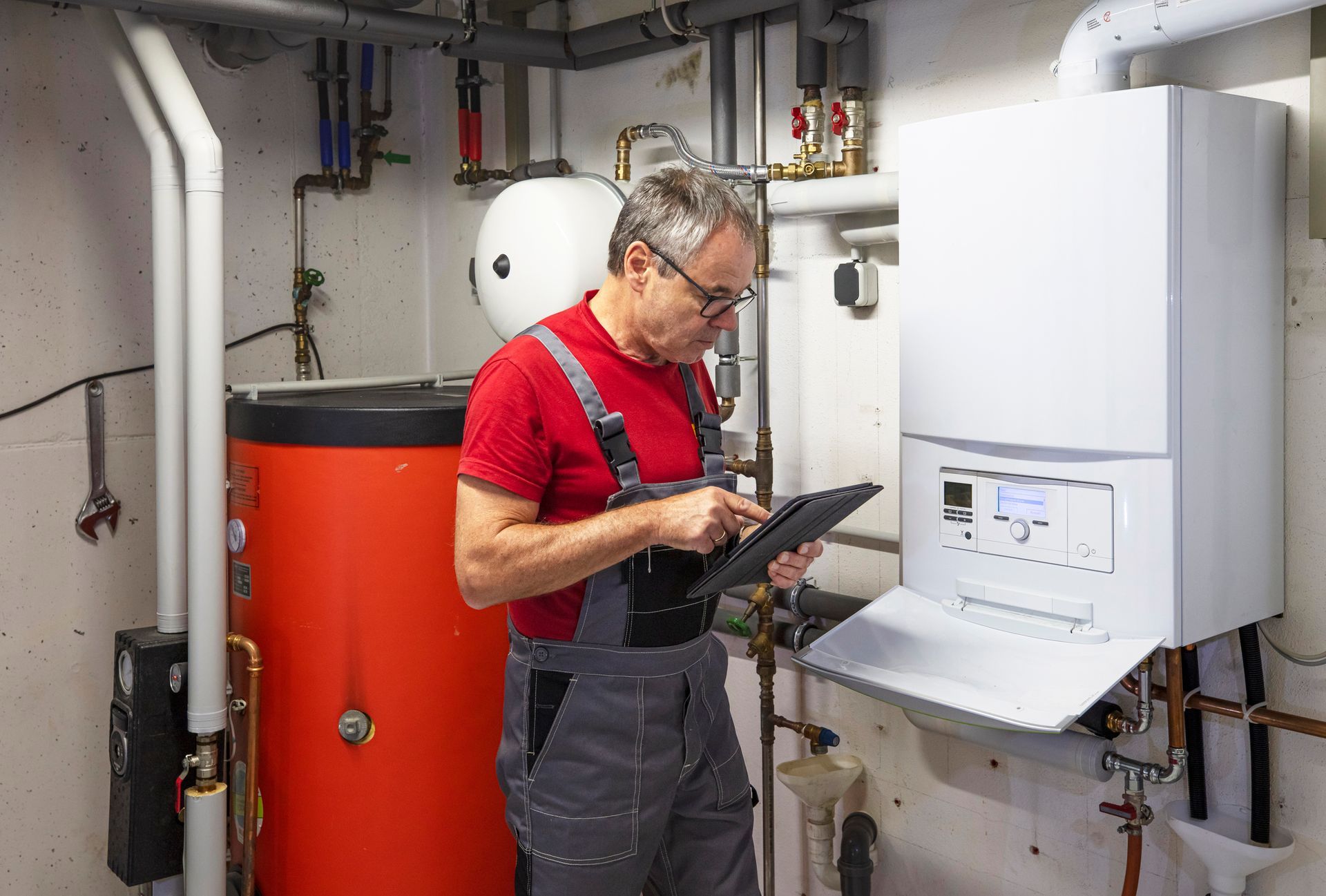 Image of a HVAC technician checking a white heating system in a basement.— Kingsport, TN — Johnny's Electrical & HVAC Image of a HVAC technician checking a white heating system in a basement.— Kingsport, TN — Johnny's Electrical & HVAC