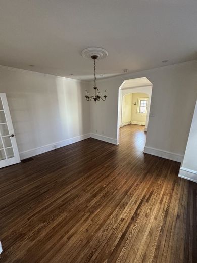 A living room with hardwood floors and a chandelier hanging from the ceiling.