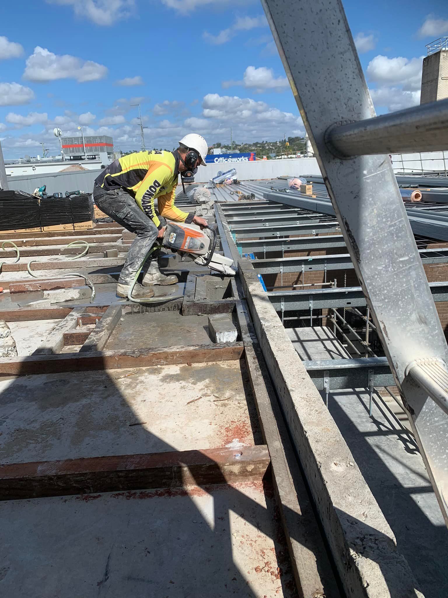 Construction Worker Cutting Concrete on a Rooftop — Dondarra Concrete Cutting & Drilling in Parkhurst, QLD