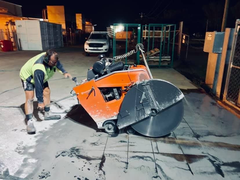 Man Operating a Concrete Saw Outdoors at Night — Dondarra Concrete Cutting & Drilling in Parkhurst, QLD