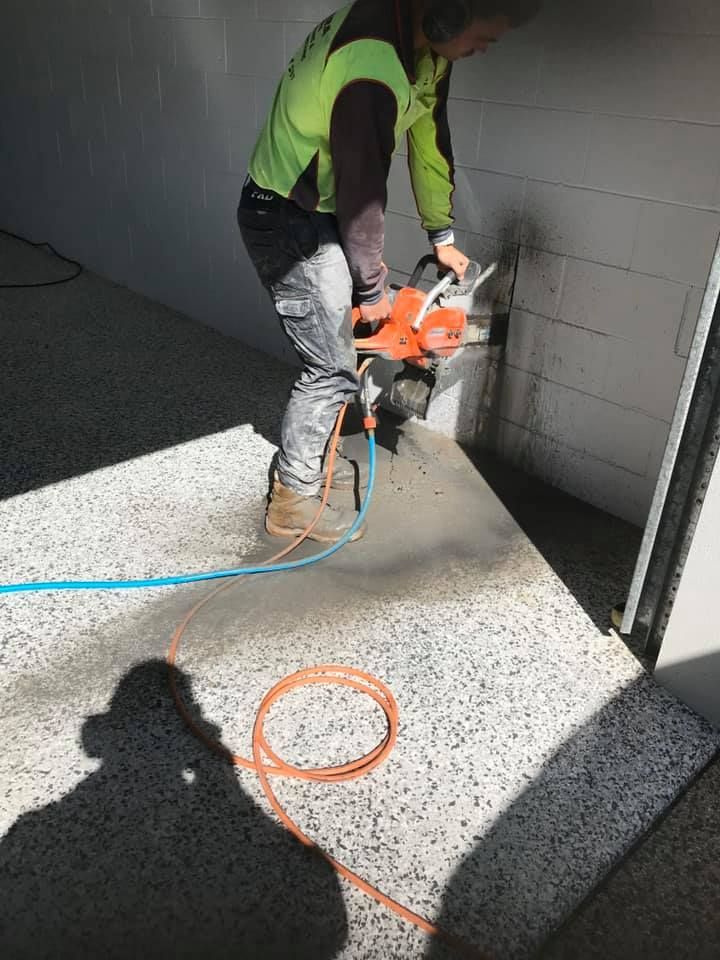 Person in Safety Vest Using a Concrete Saw on a Wall — Dondarra Concrete Cutting & Drilling in Parkhurst, QLD