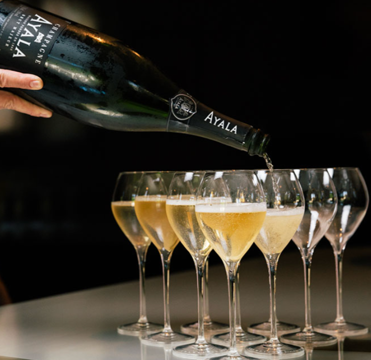 a bottle of ayala being poured into glasses.
