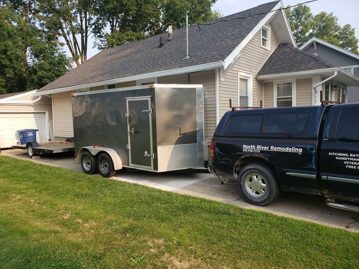 a trailer is being towed by a truck in front of a house .