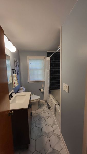 a bathroom with a sink , toilet , shower and window .