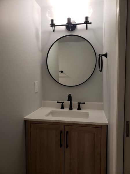 a bathroom sink with a round mirror above it .