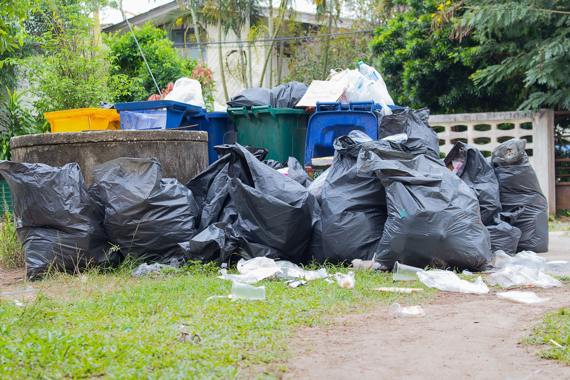 A pile of garbage bags sitting on top of a lush green field.
