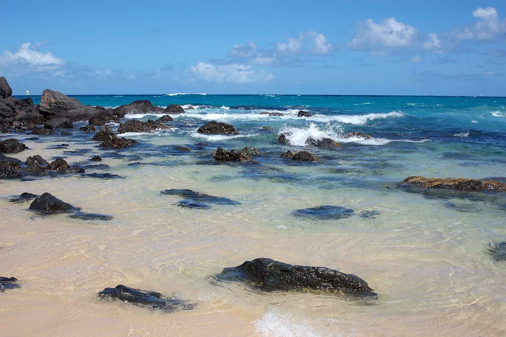 A Beach With Rocks In The Water And Waves Crashing On The Shore — Climatech In Nambour, QLD