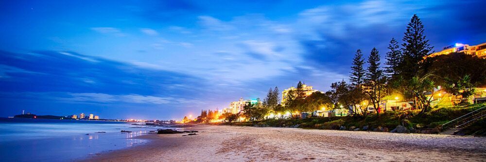 A Beach At Night With Trees And Lights On The Shore — Climatech In Mooloolaba, QLD