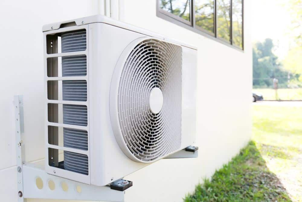 A White Air Conditioner Is Mounted On The Side Of A Building — Climatech In Marcoola, QLD