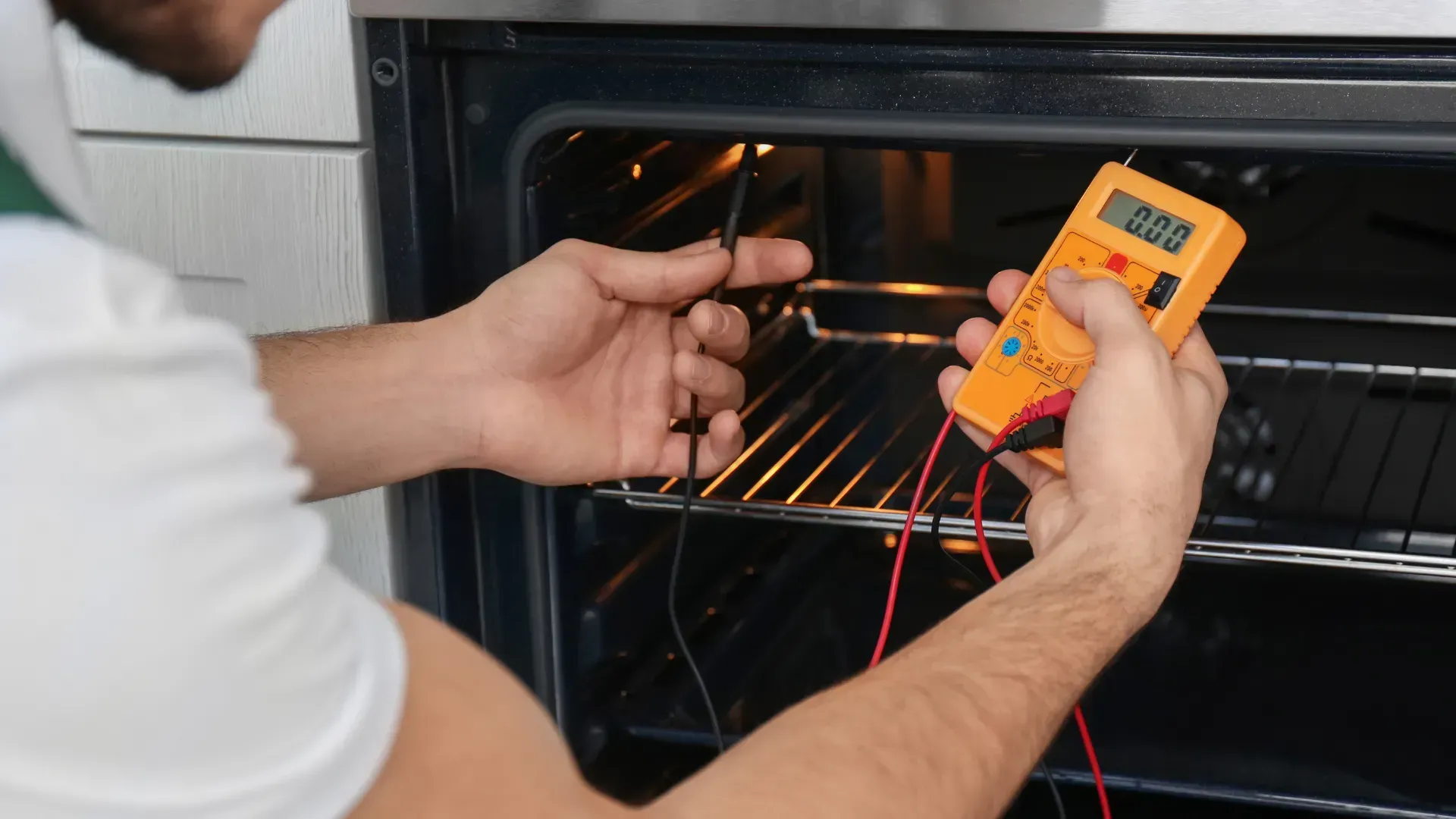 A man is using a multimeter to check the temperature of an oven.