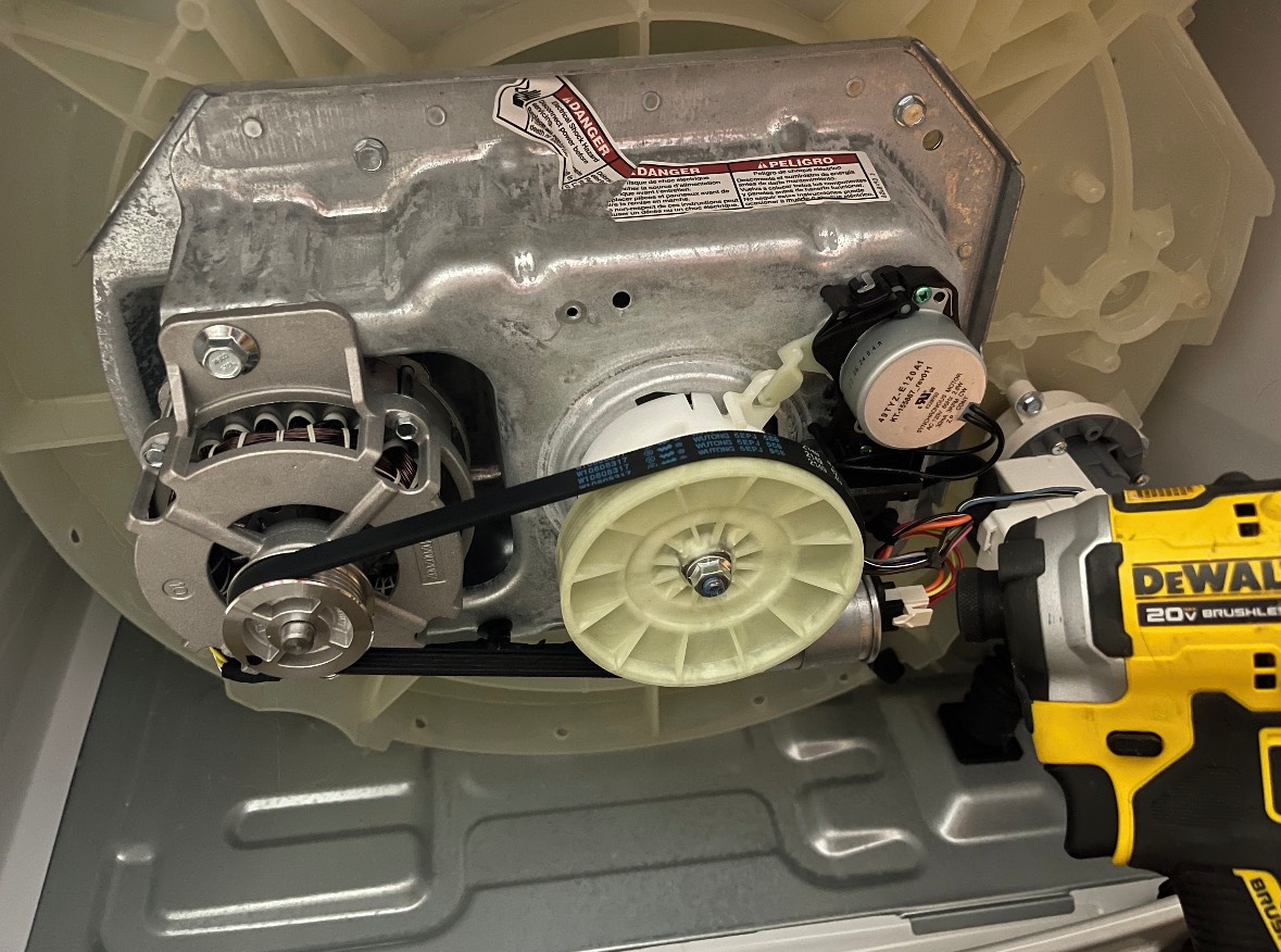 A dewalt drill is being used to fix a washing machine motor.