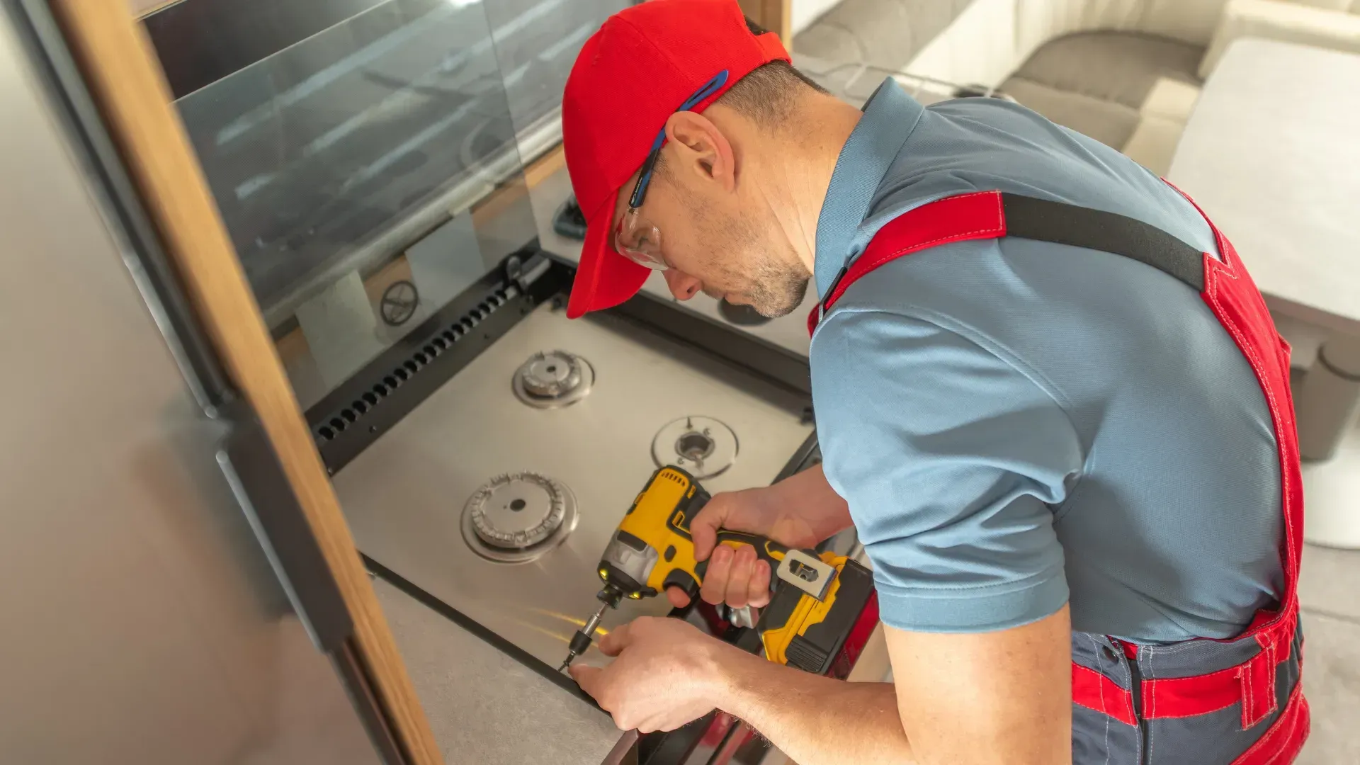 A man is working on a stove in a kitchen.