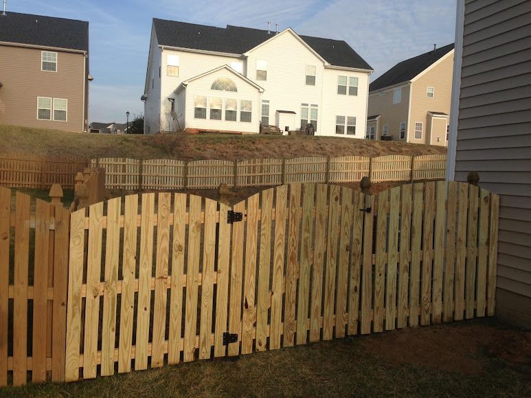 Backyard with a wooden fence in front of suburban houses under a cloudy sky