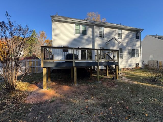 Backyard deck on a two-story beige house with a staircase and winter trees nearby