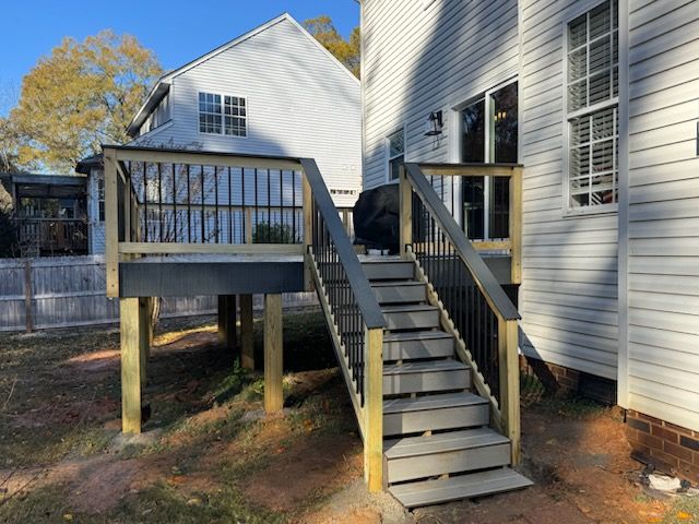 Wooden ramp and stairs leading to a raised deck beside a white house outdoors
