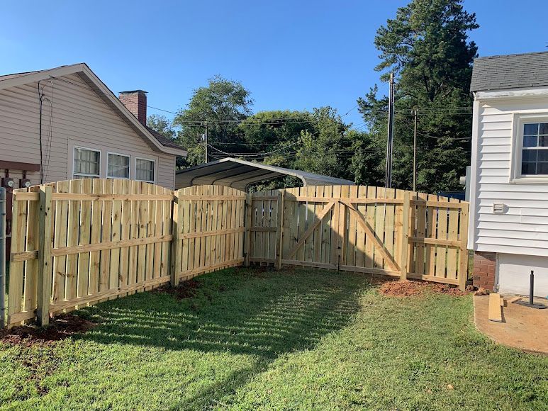 Backyard with wooden fence between two houses, green lawn, and clear blue sky
