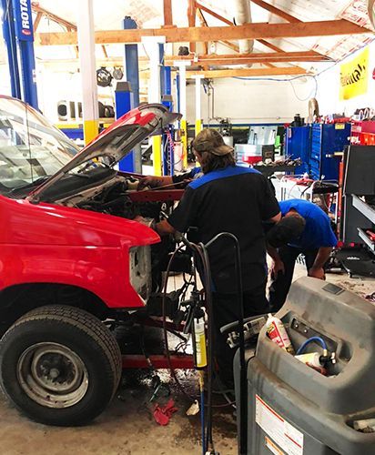 A red truck is being worked on in a garage