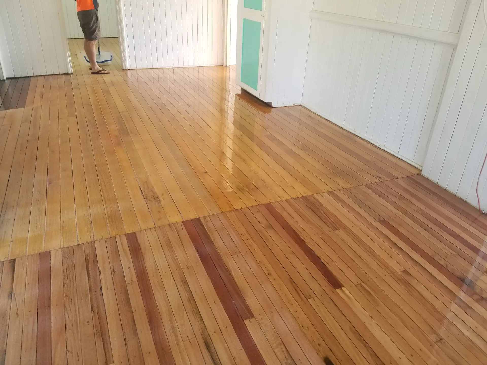 Newly polished wooden floor with a person in the background. The floor has a glossy finish. — The Good Wood Polished Timber Floors in Westbrook, QLD