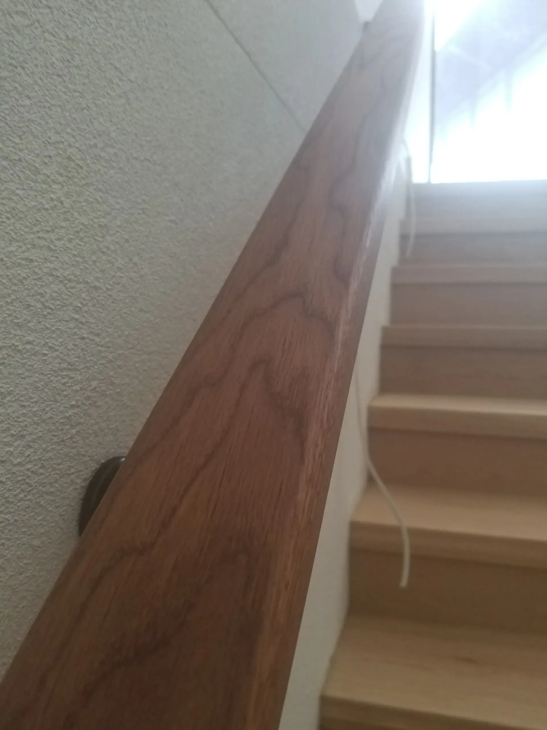 Wooden handrail on a staircase, light brown, against a white wall and light wood steps. — The Good Wood Polished Timber Floors in Oakey, QLD