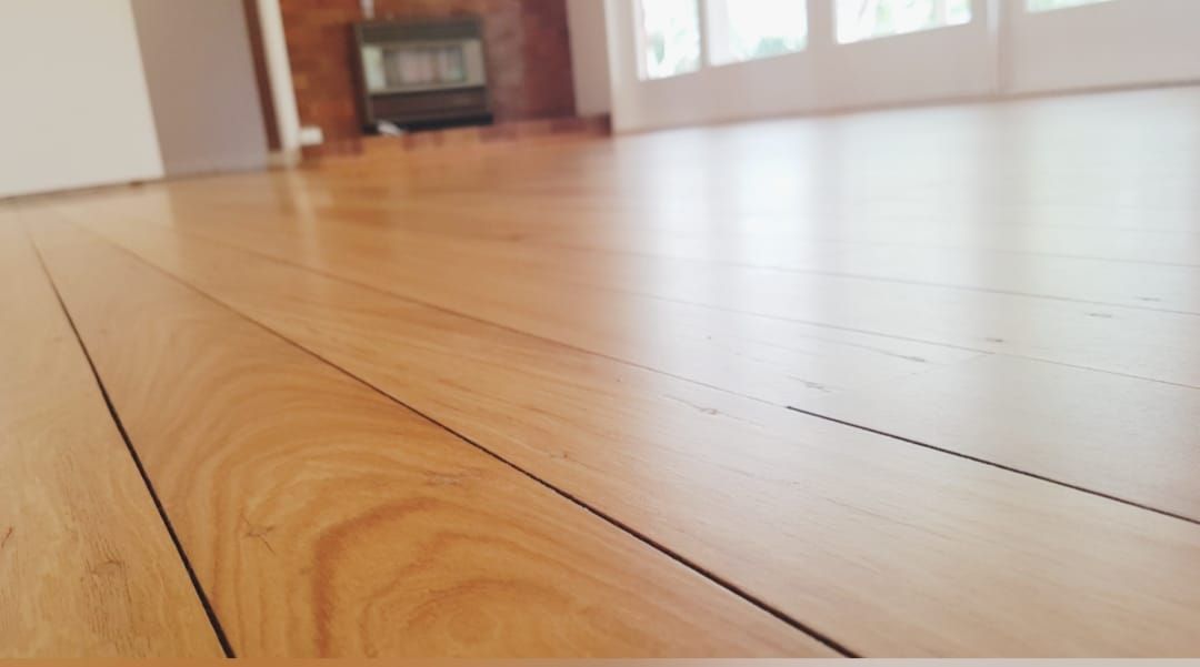 Wooden floorboards in a room, with a fireplace and windows in the background. — The Good Wood Polished Timber Floors in Oakey, QLD
