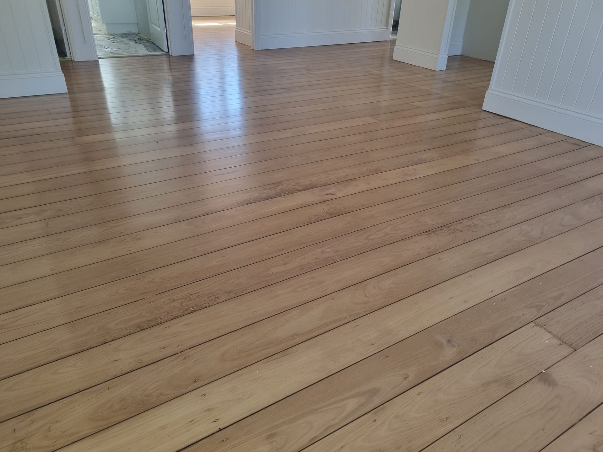 Wooden floorboards in a room, reflecting light.