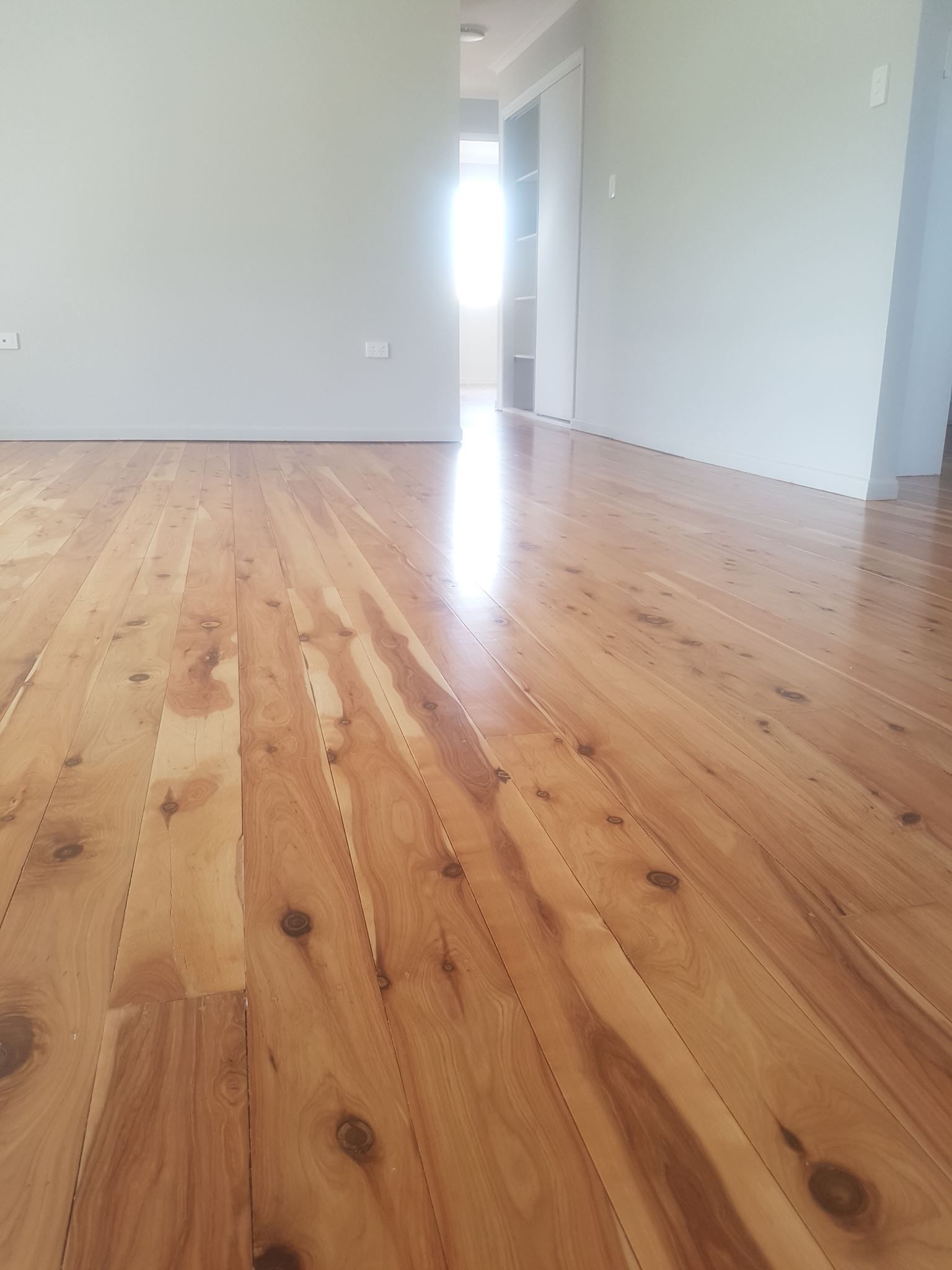 Newly polished wooden floorboards in a light-filled room, leading to a doorway. — The Good Wood Polished Timber Floors in Pittsworth, QLD