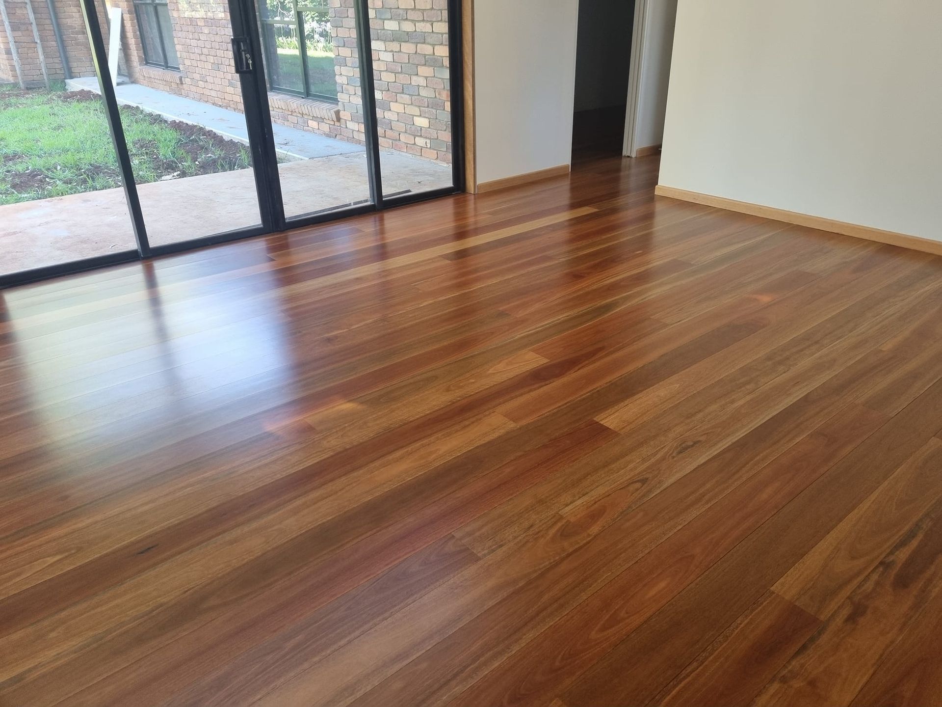 Shiny Reddish-brown Hardwood Floor in a Room — The Good Wood Polished Timber Floors in Gatton, QLD
