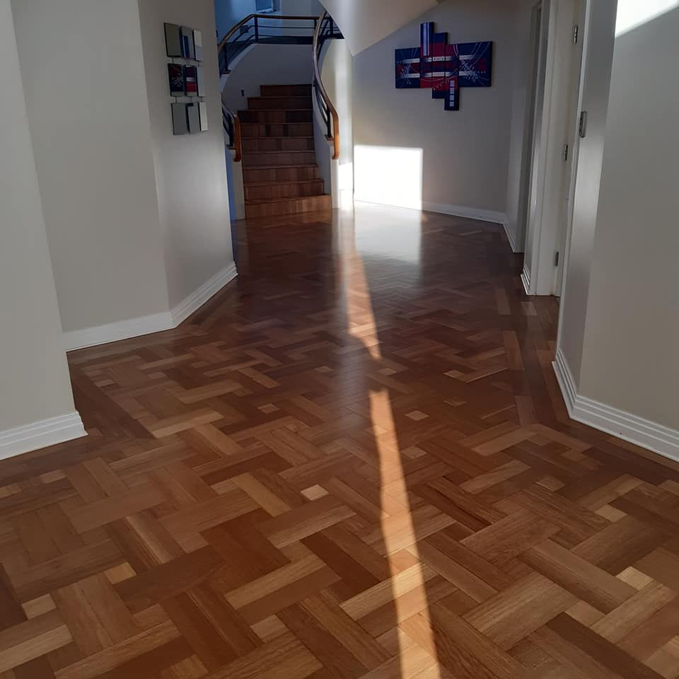 Hallway with parquet flooring, sunlight streaming in. Stairs and artwork visible in the background. — The Good Wood Polished Timber Floors in Westbrook, QLD