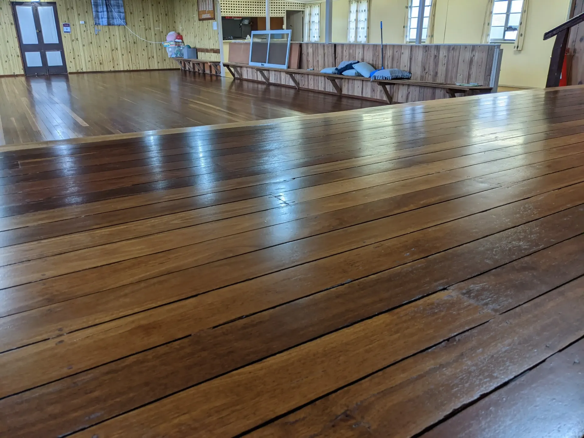 Wooden floor in a room, reflecting light. Benches and doorway in background. — The Good Wood Polished Timber Floors in Highfields, QLD