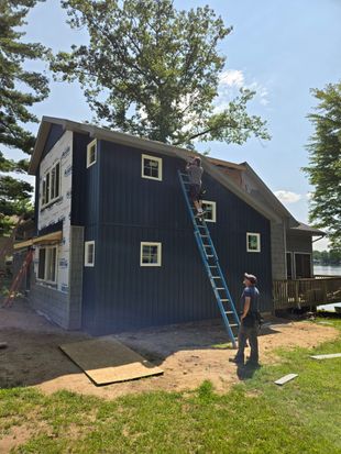 A man is installing siding on a house.