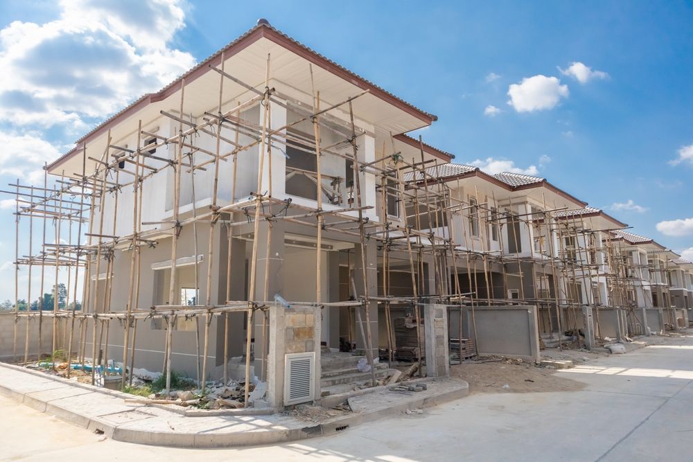 A row of houses under construction with scaffolding around them.