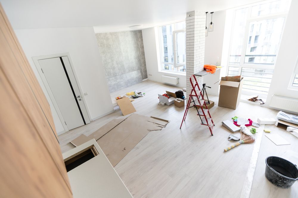 A living room under construction with a ladder and boxes on the floor.