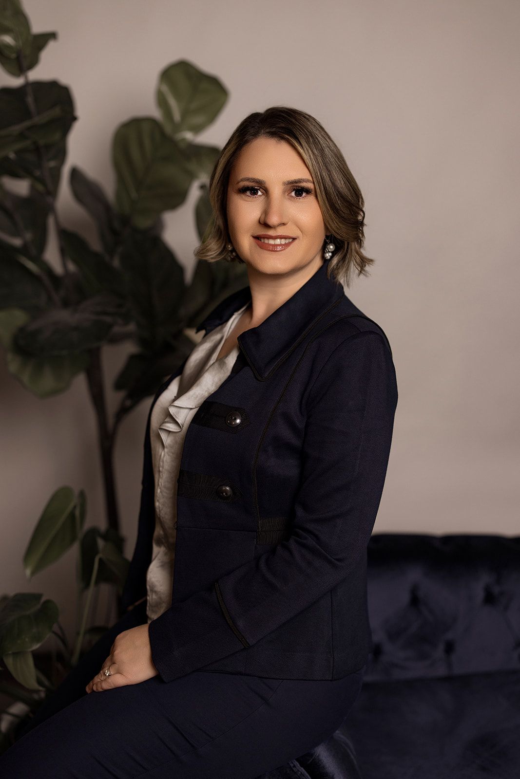 A woman is sitting at a desk with a laptop and a vase of flowers.
