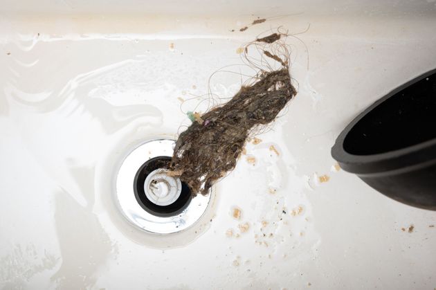 A drain in a bathroom sink with a hose coming out of it.