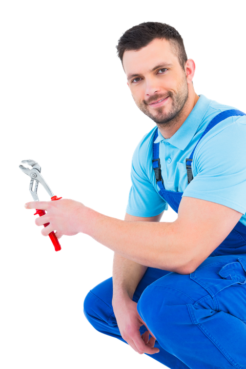 A man in blue overalls is kneeling down holding a wrench.