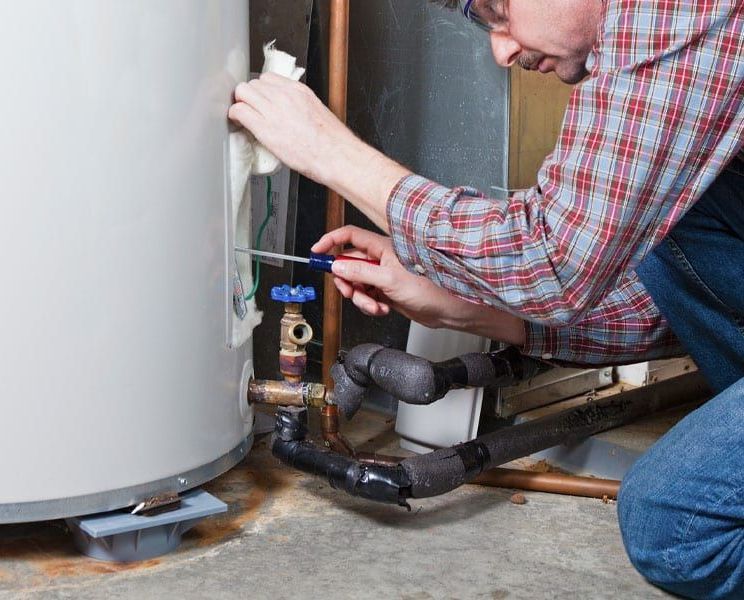 A man is fixing a water heater with a screwdriver.