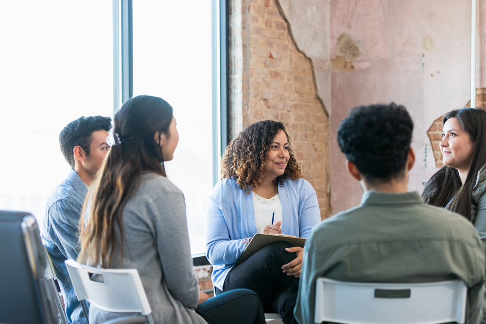 A group of people are sitting in a circle talking to each other.