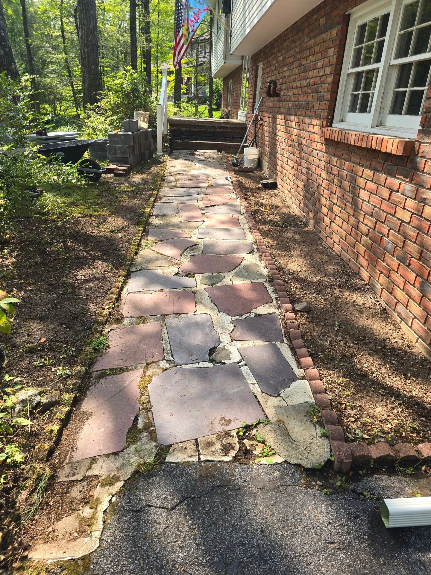 A stone walkway leading to a house with a brick wall.