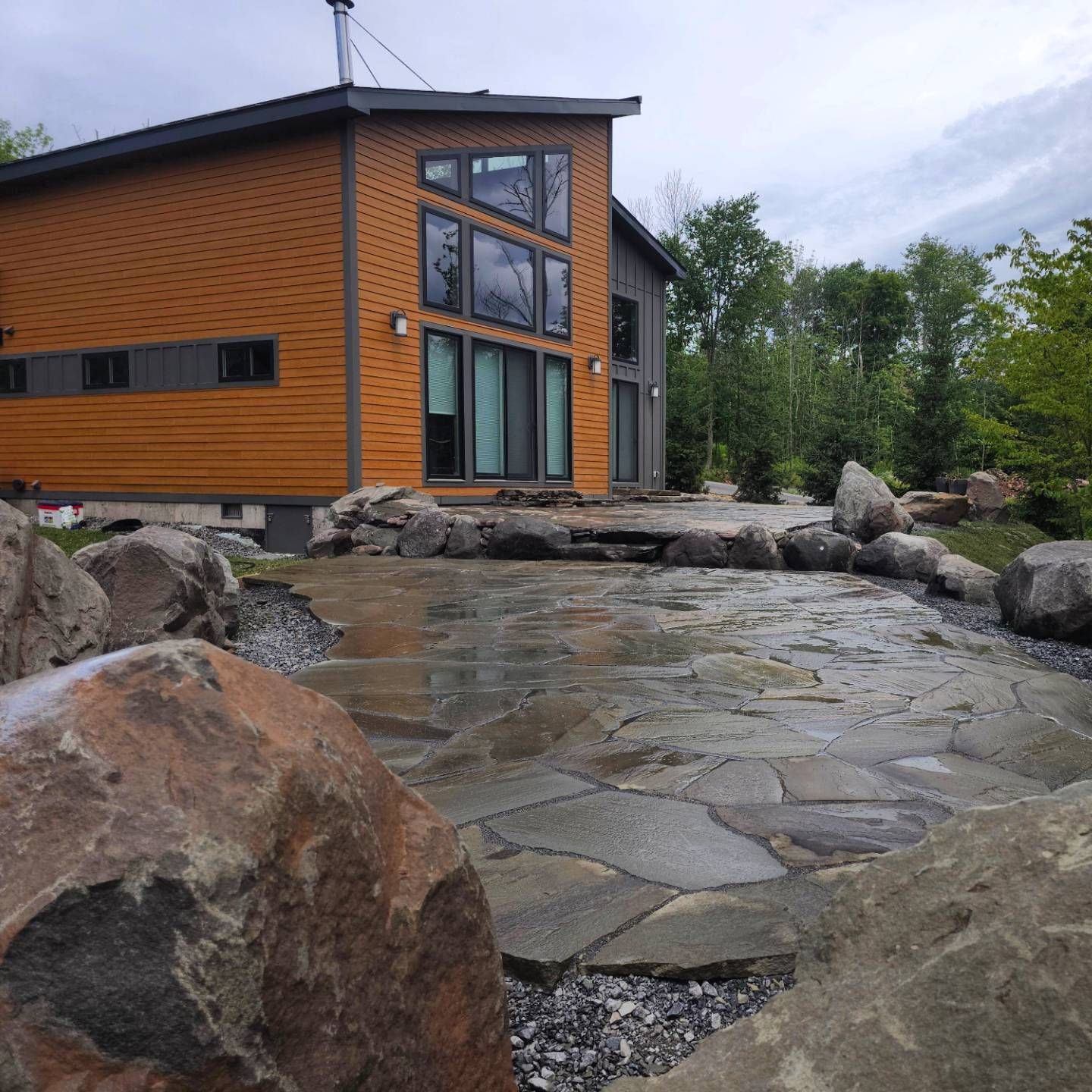 A house with a lot of windows is surrounded by rocks