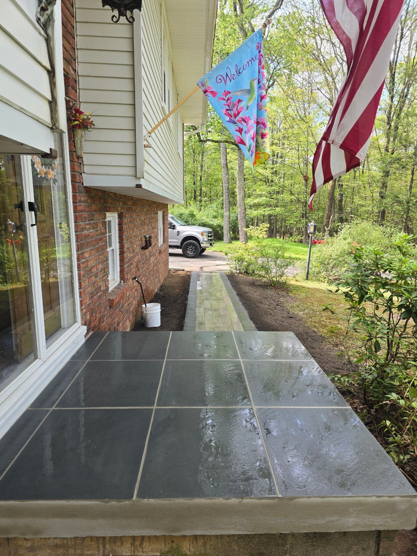 A walkway leading to a house with a flag hanging from the side of it.