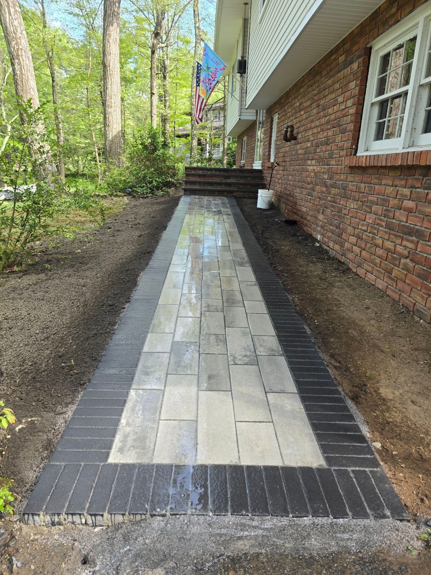 A black and white walkway leading to a brick house.