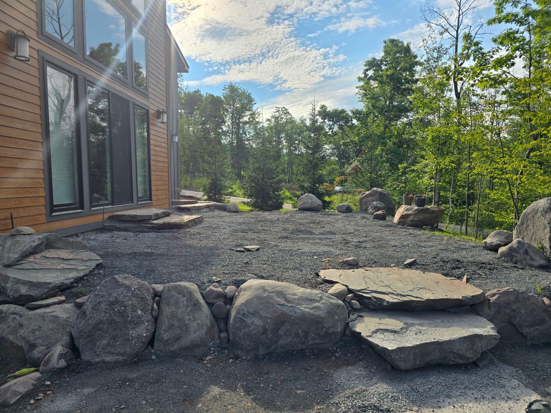 A patio with rocks and trees in front of a house.