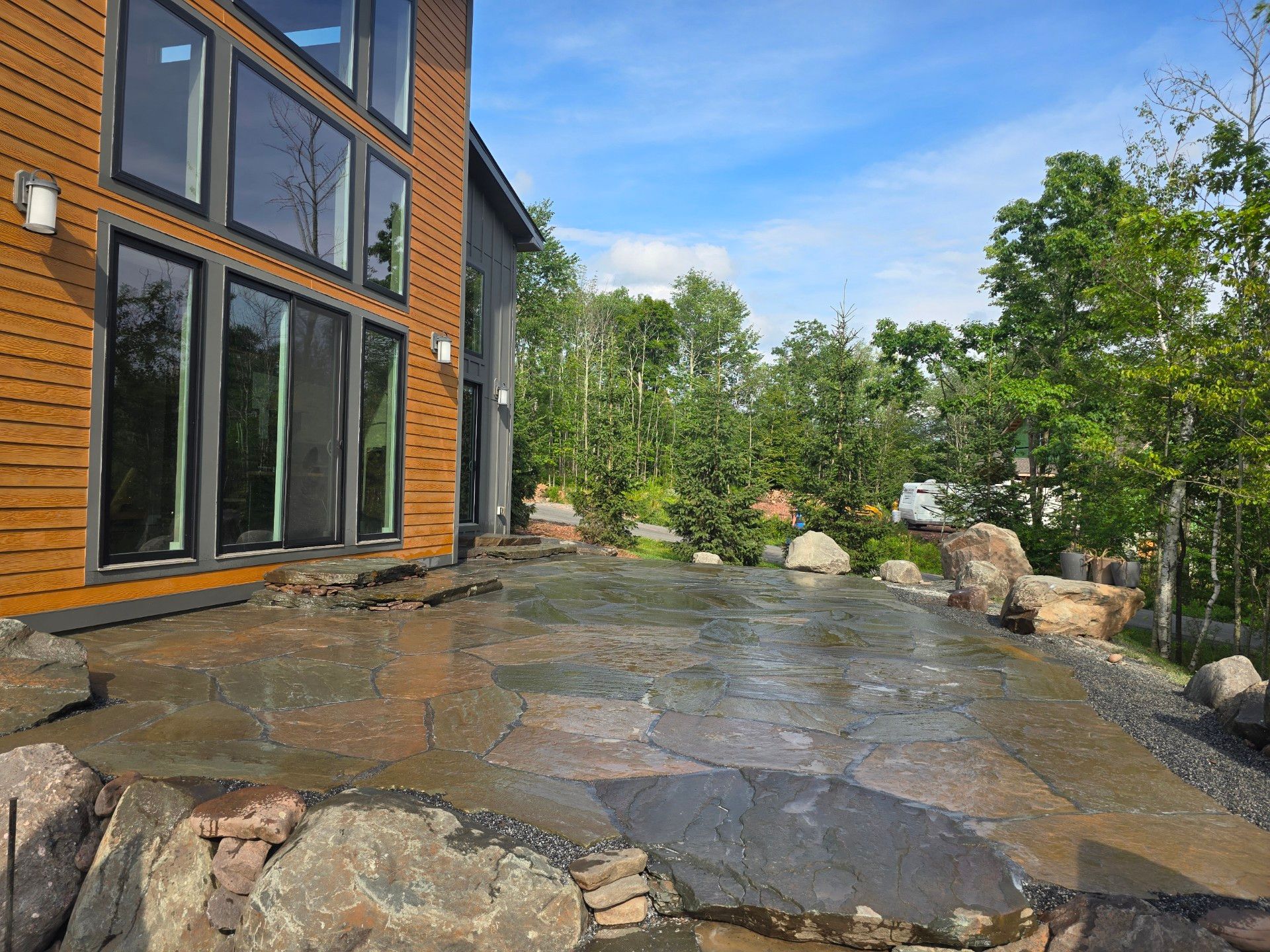 A large house with a lot of windows is surrounded by trees and rocks.