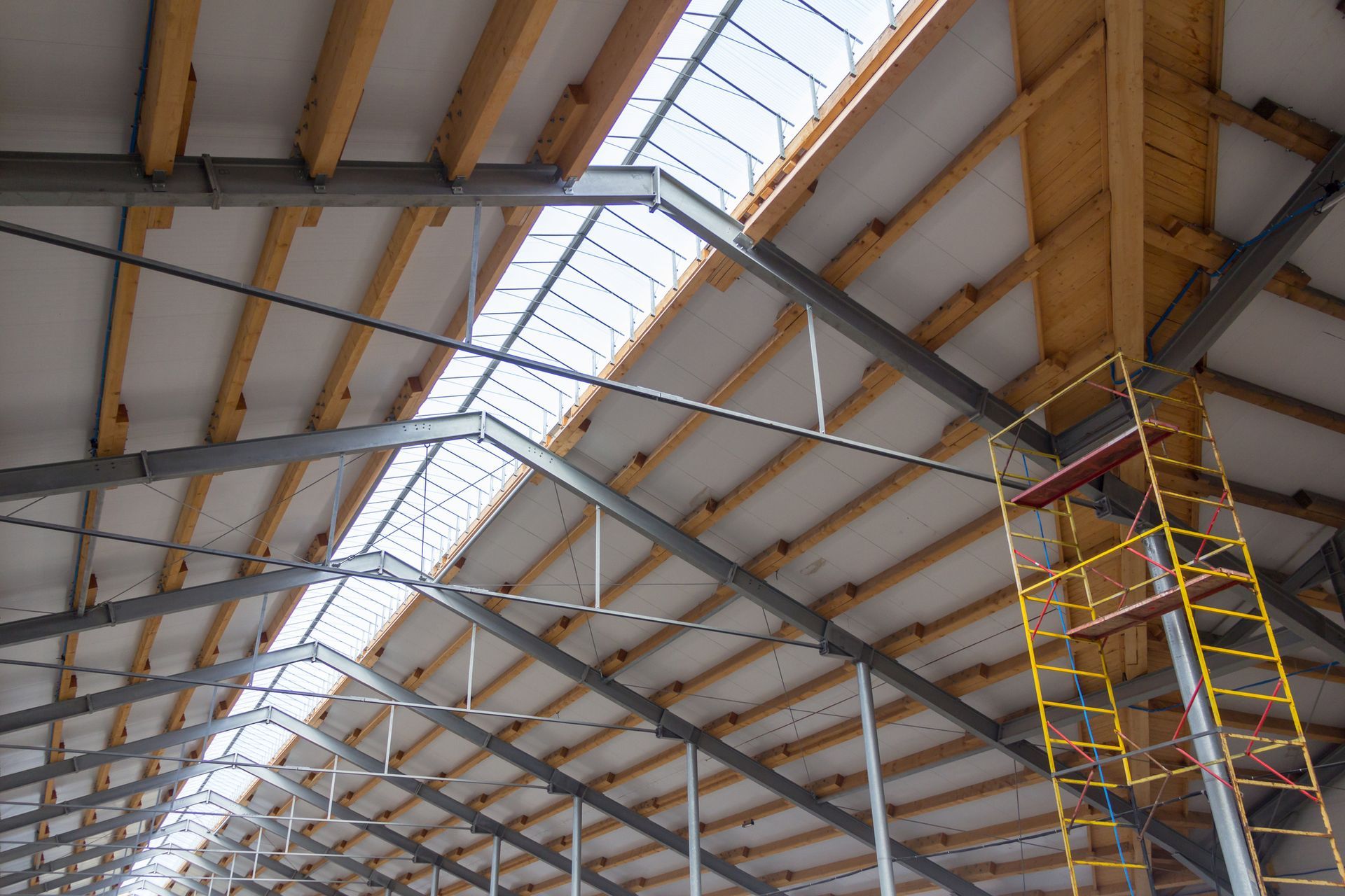 The ceiling of a building with wooden beams and metal beams.