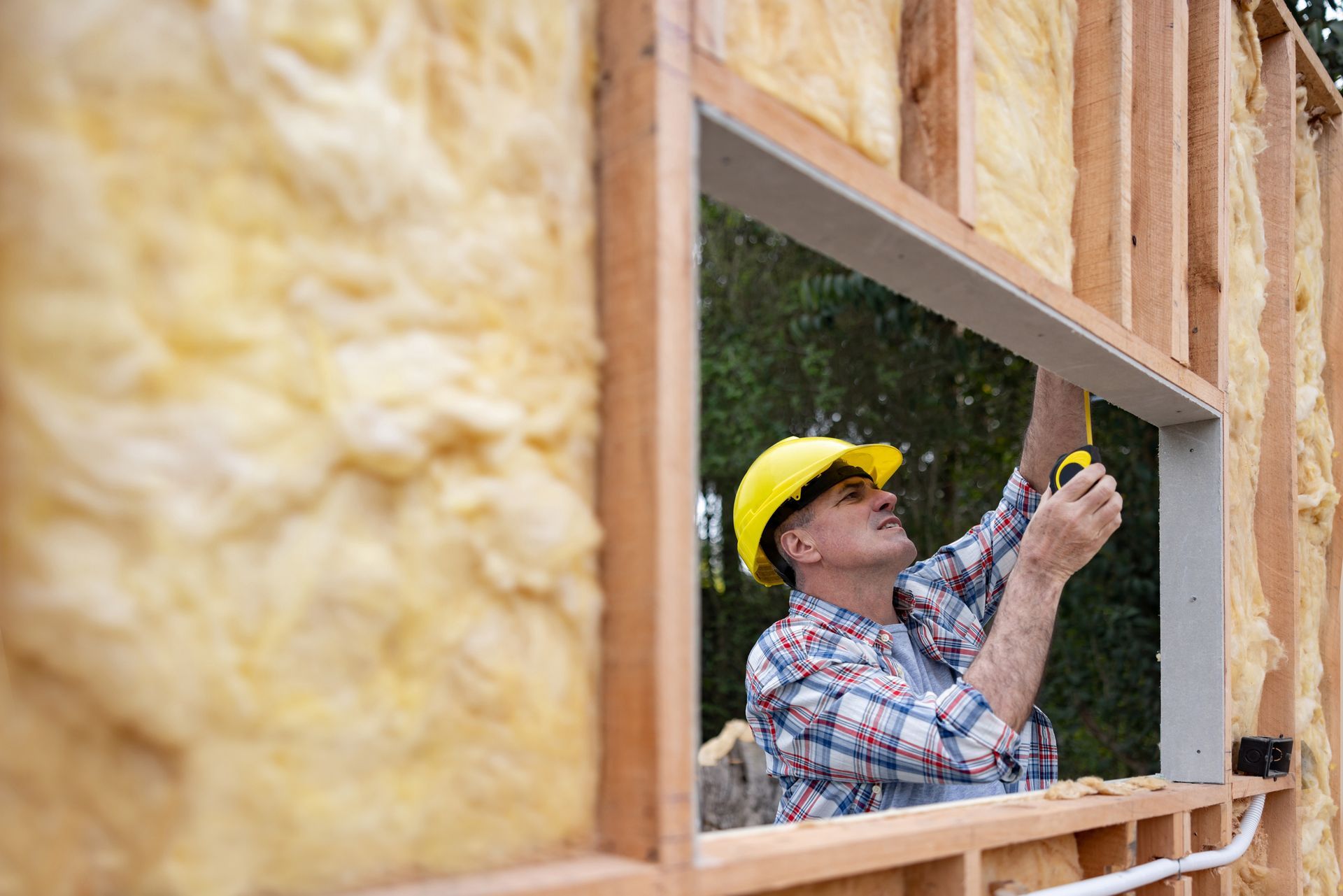 A man is measuring a window frame with a tape measure.