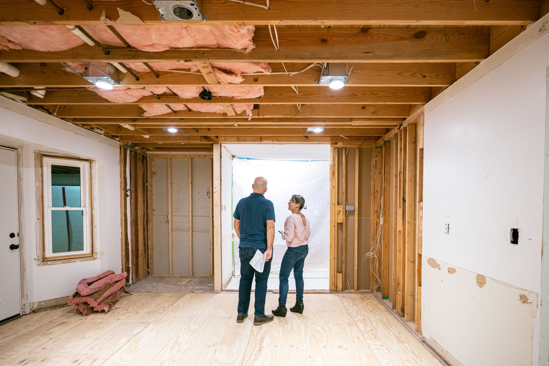 A man and a woman are standing in a room under construction.