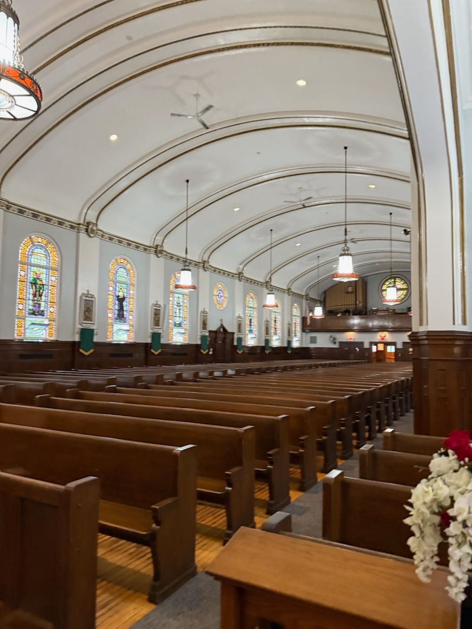 A church with rows of wooden benches and stained glass windows