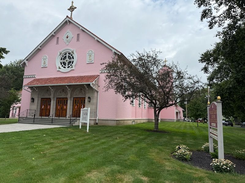 A pink church with a sign in front of it